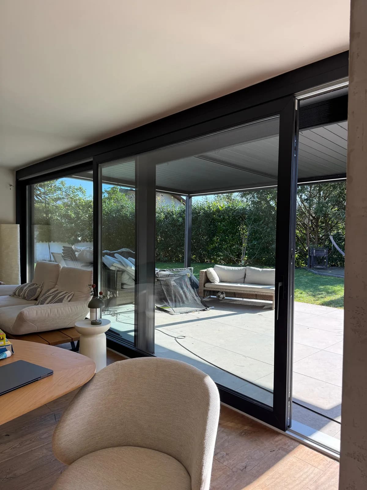 Innenansicht: anthrazitfarbene Aluminium-Hebe-Schiebetuer im Wohnbereich mit Sitzsack, Vasen und Blick in den Garten mit Sitzecke — Referenzprojekt Fenster Labisch, Saarland